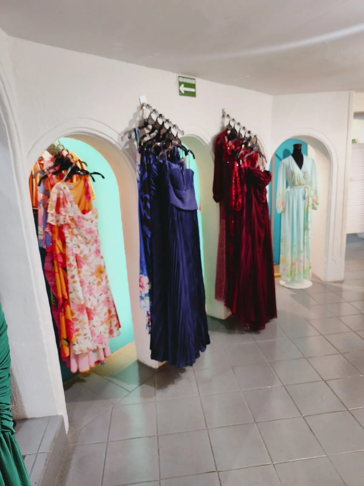 Interior de Colors: arcos blancos con nichos turquesa y vestidos colgados