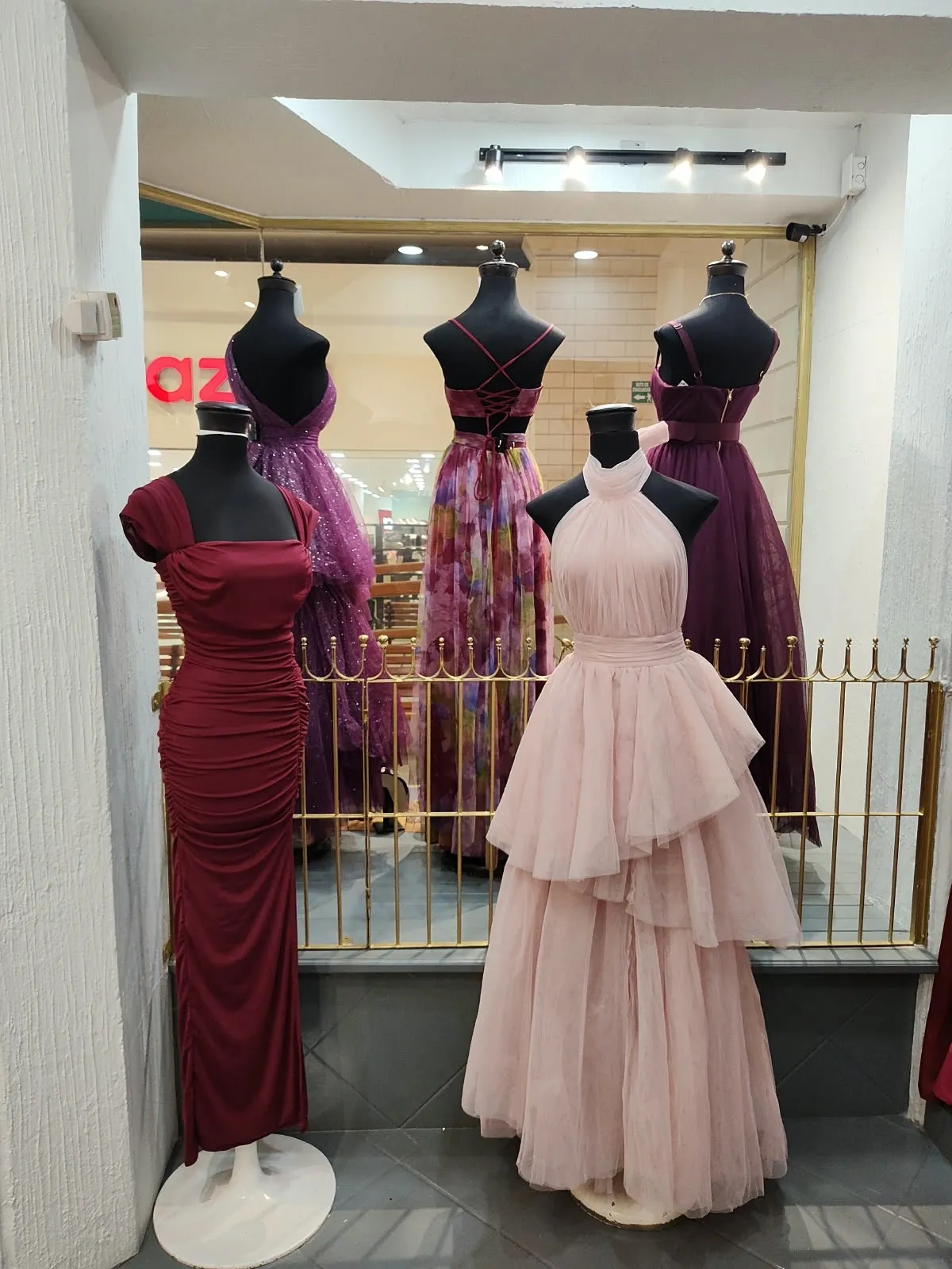 Vestido vino ajustado y vestido rosa palo de holanes en maniquí